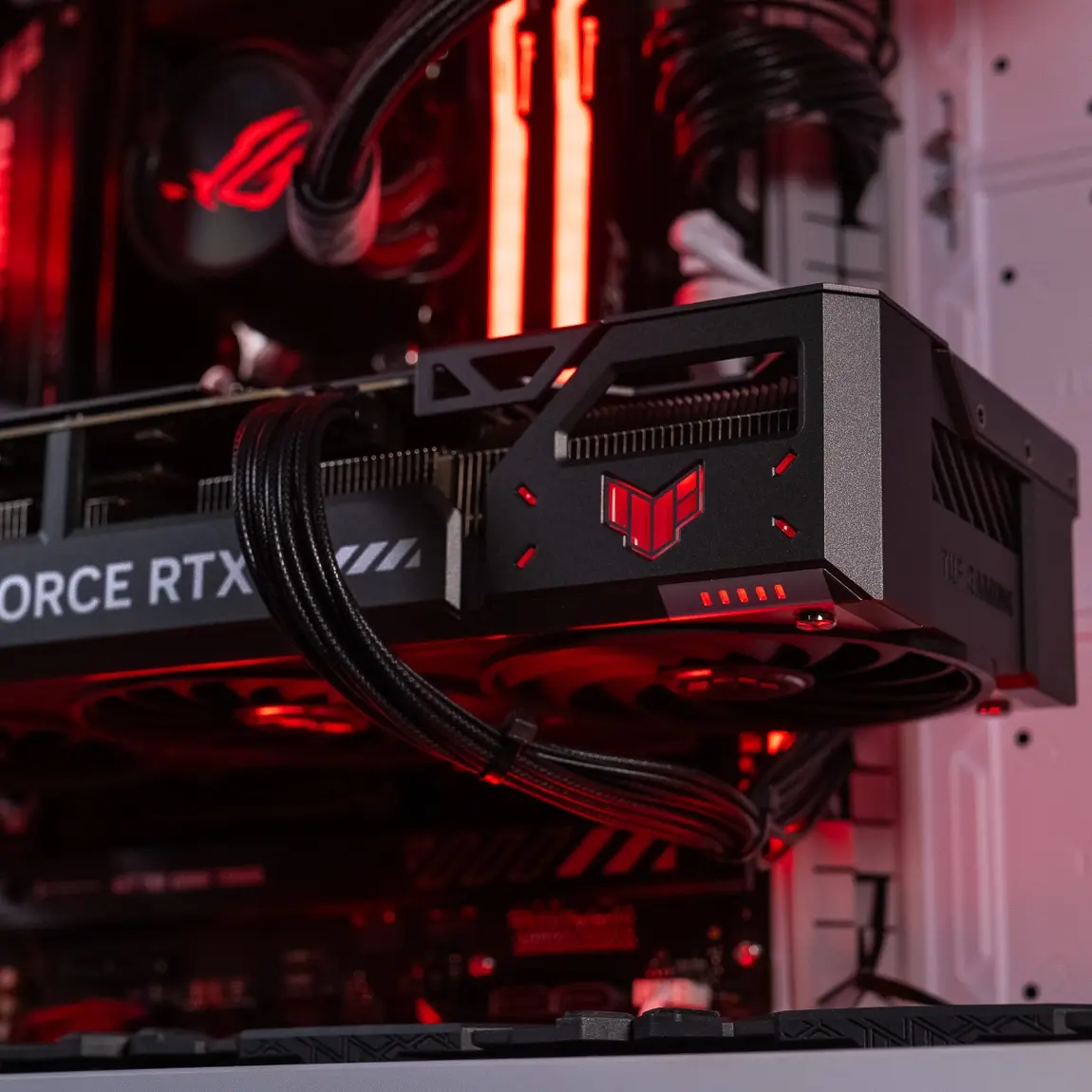 Carte graphique TUF Gaming NVIDIA GeForce RTX installée dans un PC gamer avec éclairage rouge Cette image présente une carte graphique TUF Gaming NVIDIA GeForce RTX montée sur une carte mère ASUS, avec son connecteur PCIe bien visible et les câbles d’alimentation branchés. Elle illustre visuellement la vérification essentielle de la connexion GPU lors du dépannage d’un PC qui ne démarre pas. Une carte mal insérée ou un câble d’alimentation oublié peut bloquer totalement le système. Il est recommandé de retirer et rebrancher la carte graphique, et de tester un démarrage via la puce graphique intégrée si le processeur en dispose, en connectant l’écran directement à la sortie vidéo de la carte mère. Cette image est idéale pour renforcer cette procédure de diagnostic hardware.