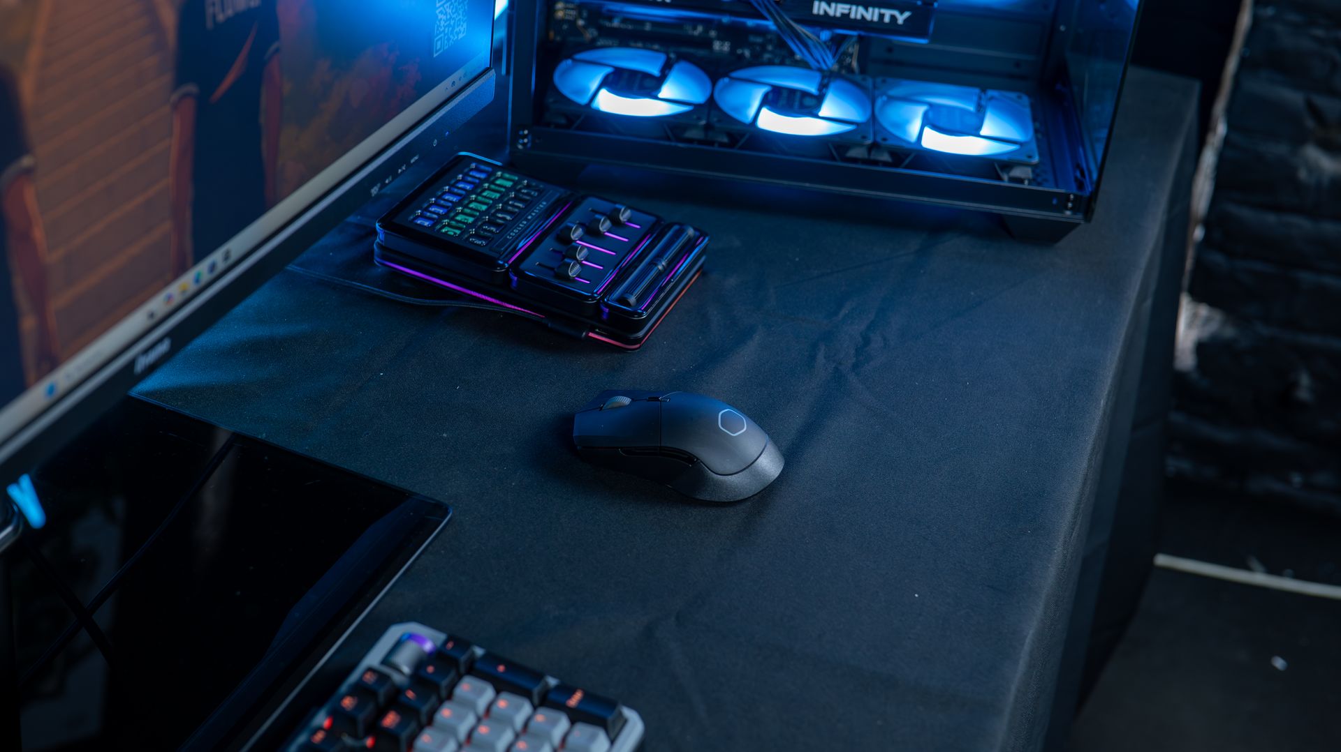 Le Cooler Master MasterHub rétroéclairé en bleu et violet à côté d'une souris gaming sans fil sur un setup de streaming chez FlowUP