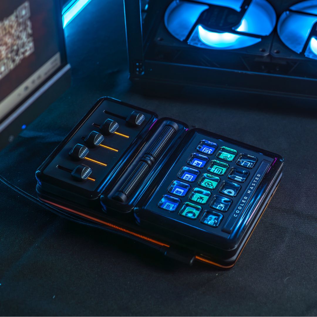 Le Cooler Master MasterHub rétroéclairé en bleu et orange, montrant la modularité des faders et des touches LCD sur un bureau de créateur chez FlowUP
