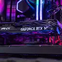 Gros plan sur la carte graphique PNY GeForce RTX 5070 installée dans le PC gamer Aqua, révélant ses caloducs en cuivre et son éclairage ambiant rose et bleu