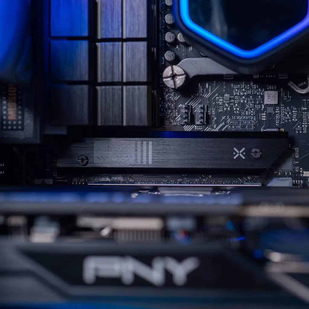 Gros plan sur le dissipateur thermique noir du SSD M.2 situé entre le processeur et la carte graphique PNY dans le PC gamer Aqua