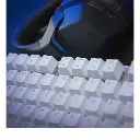 Gros plan sur les touches blanches d'un clavier mécanique gamer avec un casque audio noir en arrière-plan pour setup PC FlowUP