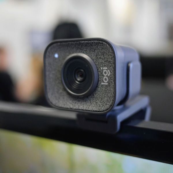 Vue de trois quarts webcam streaming Logitech StreamCam grise installée sur le haut d'un écran PC pour setup gamer FlowUP